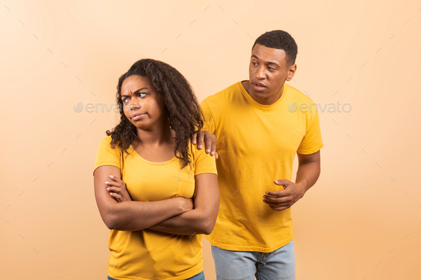 Black couple after quarrel, husband trying to talk and reconcile with offended wife, standing over