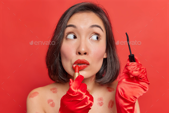 Beauty makeup. Asian lady applies lipstick and mascara uses decorative cosmetics for fabulous look w