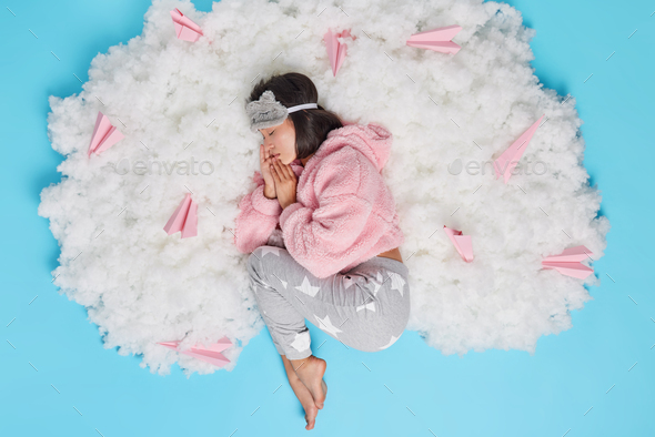 Top view of young Asian woman has enough amount of sleep every night relaxes on white cloud has perf