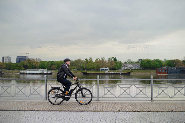 Businessman commuter on the way to work, riding bike onver bridge, sustainable lifestyle concept.