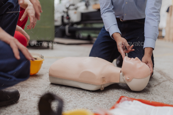 Close-up of male instructor showing first medical aid on doll during training course indoors