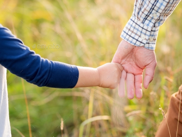 Father and son hold hands. Emotional and moral support. Man and boy shake hands. Golden hour outdoor