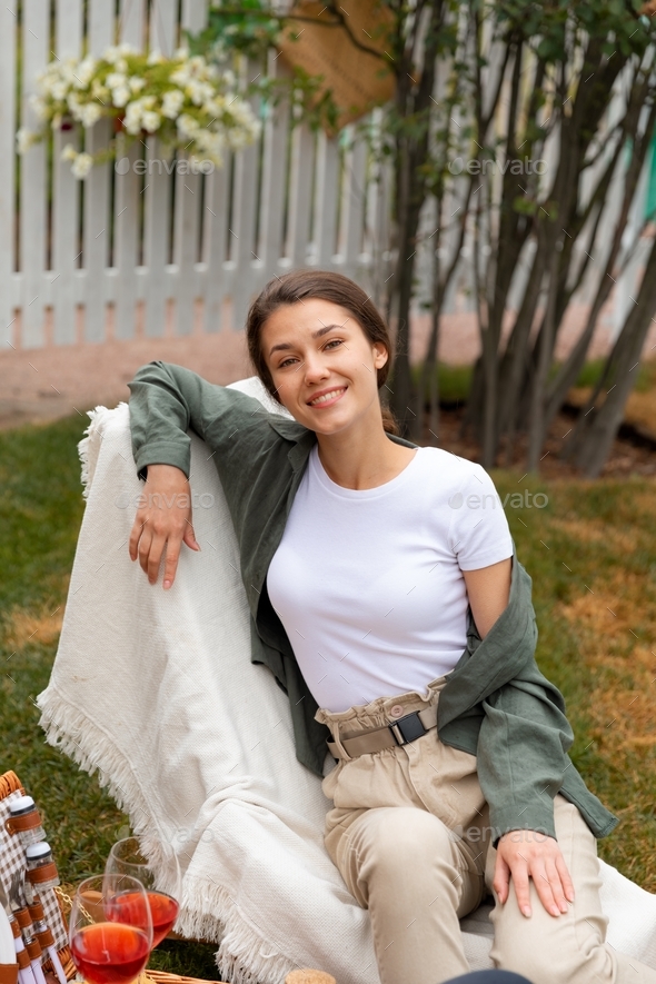 A young lady has a dating at the back yard, with lunch basket and wine - Stock Photo - Images