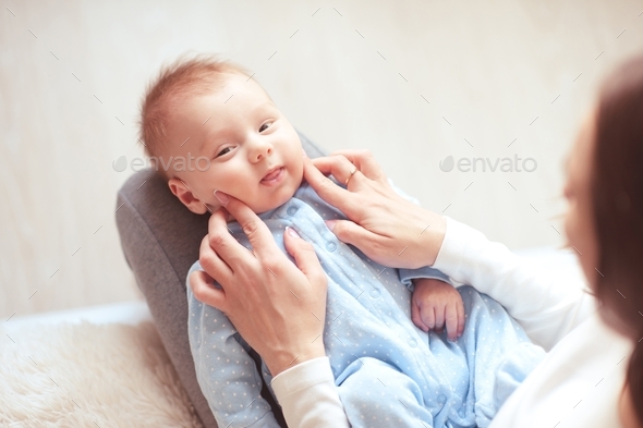 Baby boy under 1 year old wake up on mother hands wearing pajamas closeup.