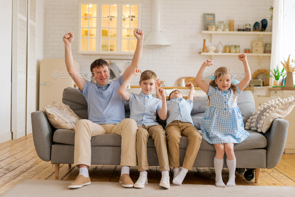 Happy overjoyed father family with small children. Sports fans watching tv game