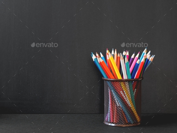 Pencil case with colored pencils on black background. Colorful stationery. Back to school concept.