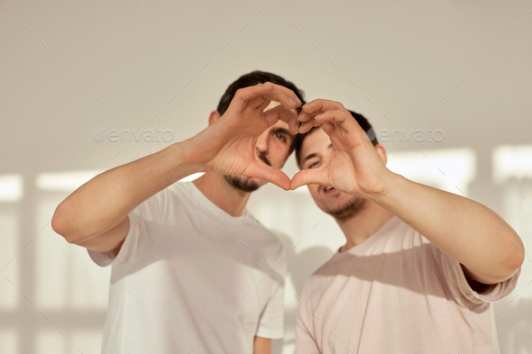 Gay couple of men make heart shape out of hands