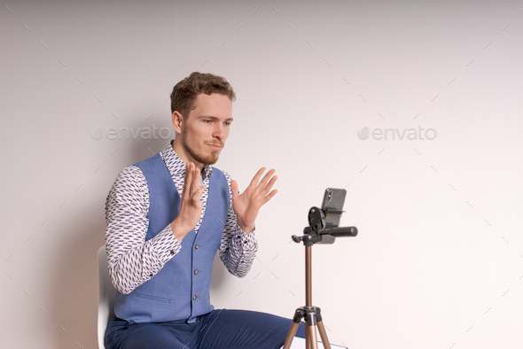 Young business man in shirt gesticulates while creating video in social