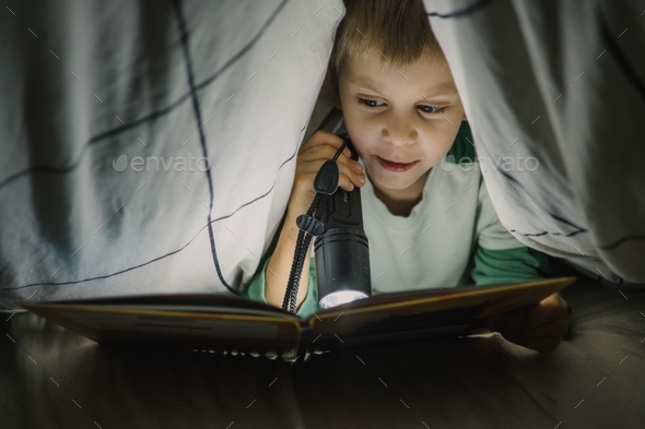 Little Boy Reading A Book At Night Covered With Blanket With Lantern ...