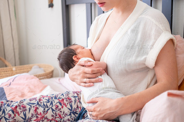 Mother breastfeeding her newborn baby. Neutral calm tones.