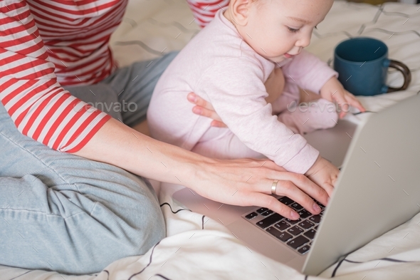 close up of hands working on laptop with little baby in hands. distance education, work at home