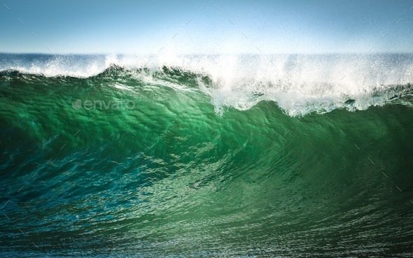 A wave of green water as the sun shines through it  - Stock Photo - Images
