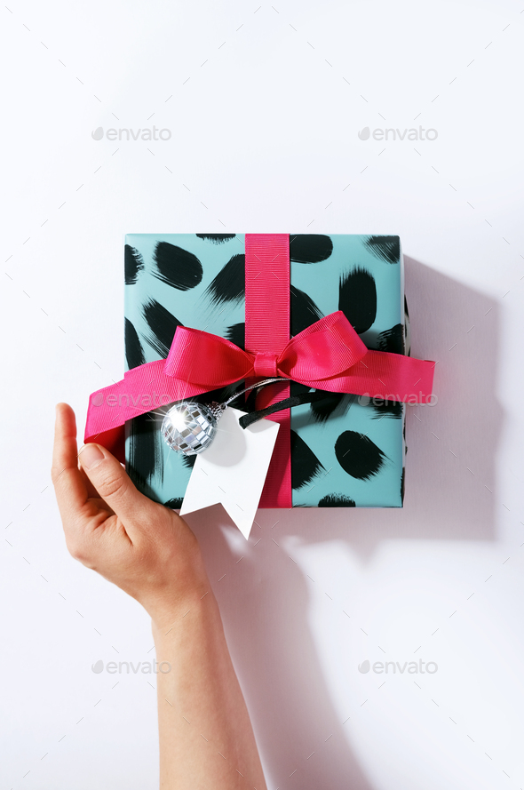 Top view photo of hand unpacking design paper gift box with pink satin ribbon bow