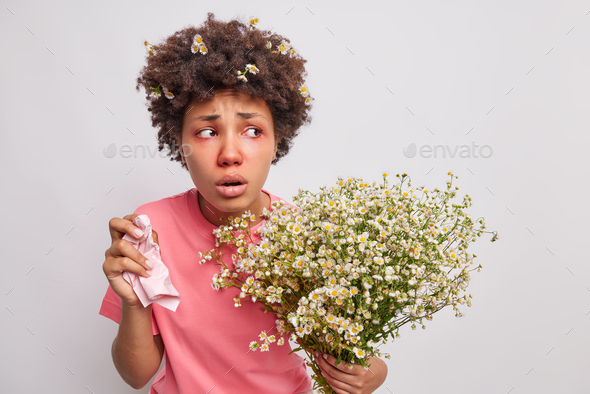 Displeased young Afro American woman feels unwell suffers from allergy symptoms holds tissue in hand