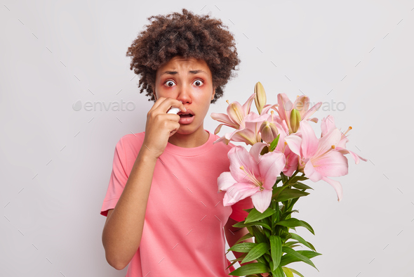 Shocked puzzled Afro American woman has allergy to lily suffers from runny nose and other unpleasant