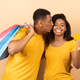 Happy black couple after shopping, woman showing credit card while man holding paper bags and - PhotoDune Item for Sale