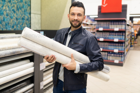 pretty shopper holding an armful of rolls of paper wallpaper in a hardware store