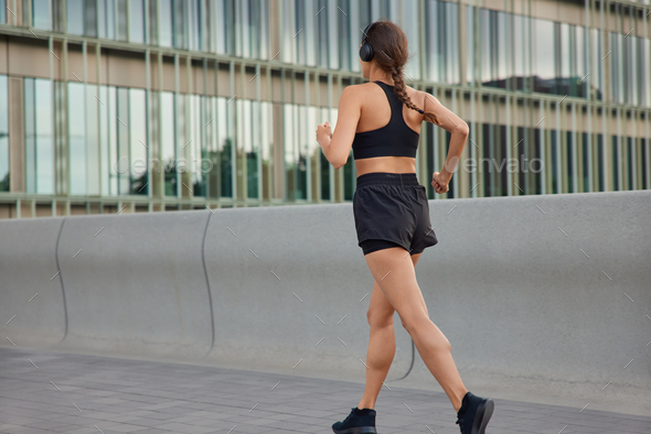Outdoor shot of active slim woman has jog exercises being physically active covers long distance wan