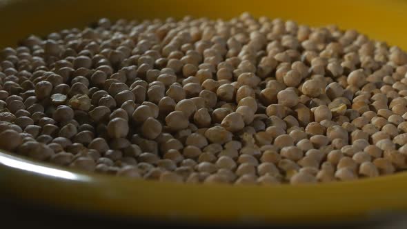 a Lot of Chickpeas Are Poured Into a Large Yellow Plate. The Plate of Chickpeas Slowly Rotates alt