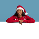 Cheerful black woman in Santa hat leaning on empty board - PhotoDune Item for Sale