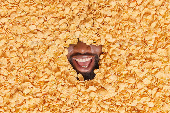 Unknown dark skinned bearded man shows only mouth has broad toothy smile fully covered with dry corn