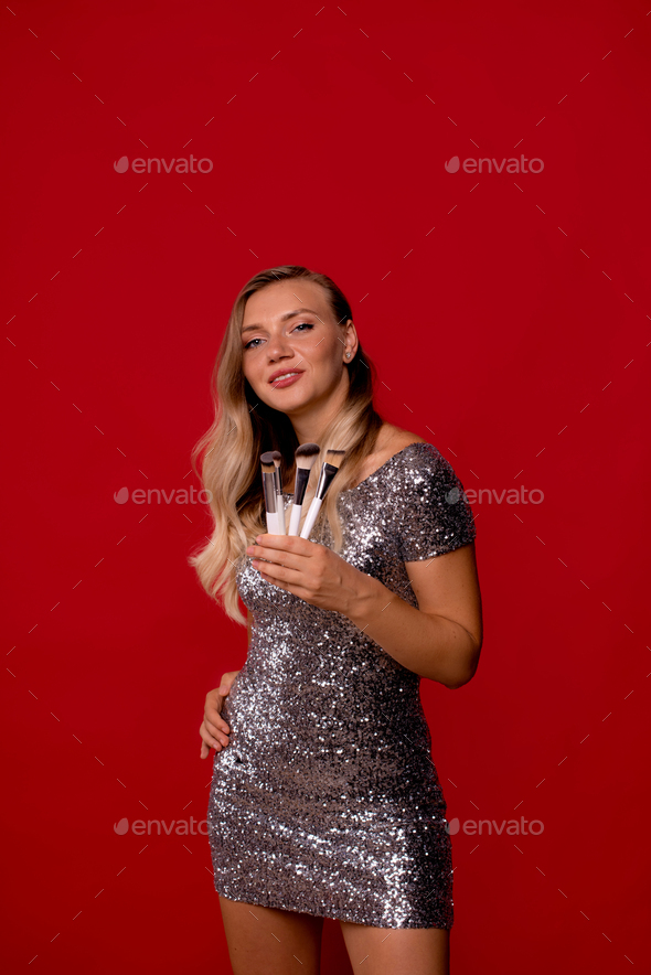 concept advertising makeup brushes, makeup courses for yourself. girl with brushes on red background