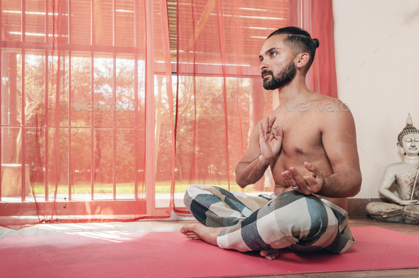 A young man with bare torso sitting in the lotus position Stock