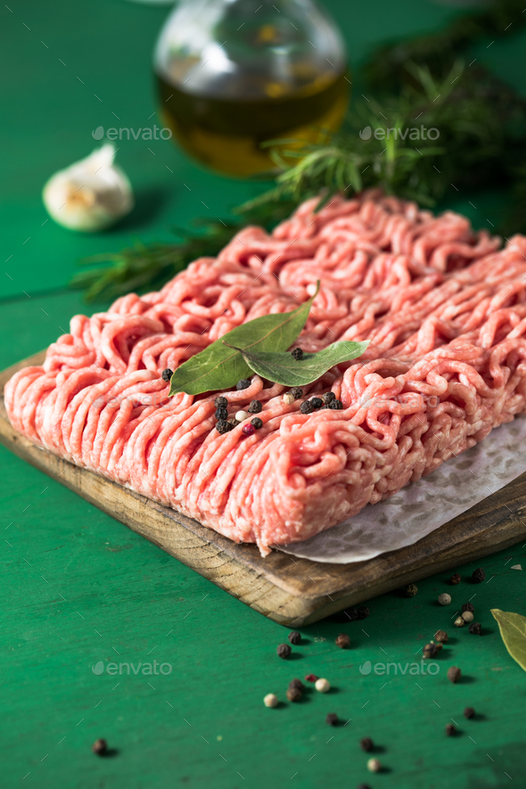 Raw Mince, minced Ground beef meat on a cutting board. Green background. Top view Stock Photo by