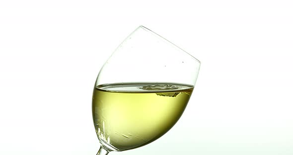 Drop of White Wine falling into Glass, against White Background, Slow motion 4K