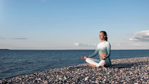 Relaxed Sportswoman Meditating in Lotus Position Sitting Crossed Legs at Nature Sunset Beach Coast alt