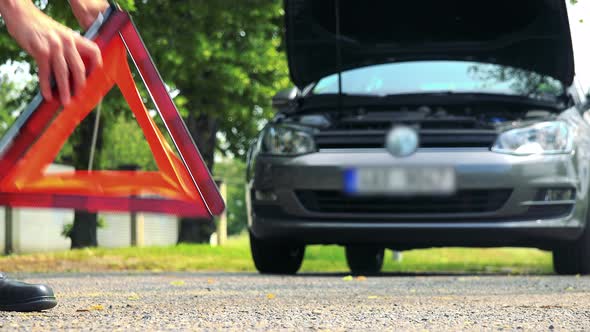 Senior Man Puts Warning Triangle in Front of the Car and Then Controls Engine of the Car alt