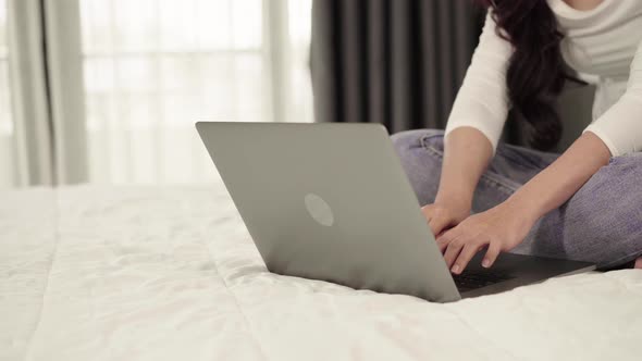 panning shot of woman using a laptop computer on bed