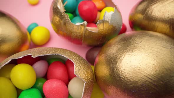 Golden Eggs with Scattered Sweets for Easter on Pink Background