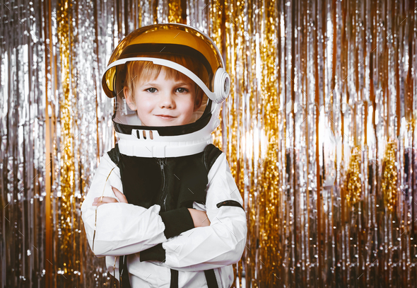 Child in fancy dress of astronaut costume having fun in background with foil curtain decorations