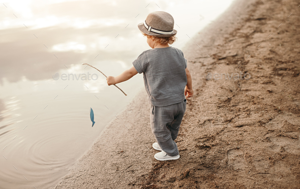 Little kid with fishing rod on river shore Stock Photo by kegfire