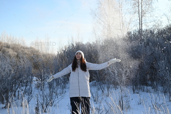 A beautiful woman with long hair in fashionable winter clothes on the  street.Catching snow. winter Stock Photo by verba0711