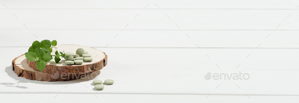 Spirulina green pills on wooden saw cut on a white table. Chlorella tablets. Green detox,  - Stock Photo - Images
