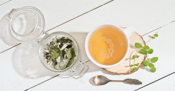 green herbal tea in white mug with fresh and dry leaves of mint and raspberry. - Stock Photo - Images
