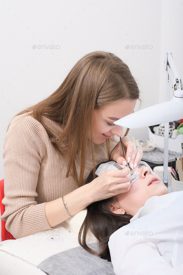 young beautician woman making false lash procedure for a client. lash extension procedure - Stock Photo - Images