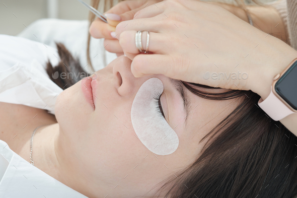 close up of caucasian woman client lying with eye closed during lash extension procedure.