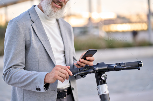 Senior old man using mobile app for bike rental renting bike in city park. - Stock Photo - Images