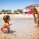 Mom plays and splashes on her baby who is laughing while standing in the sea - PhotoDune Item for Sale