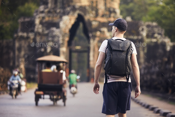 Man with backpack is walking to ancient city - Stock Photo - Images