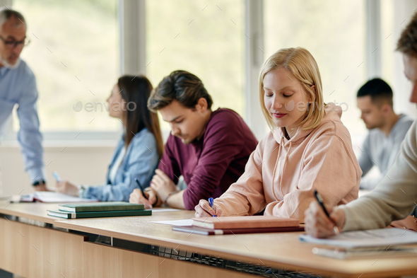 Female university student writing an exam in the classroom.