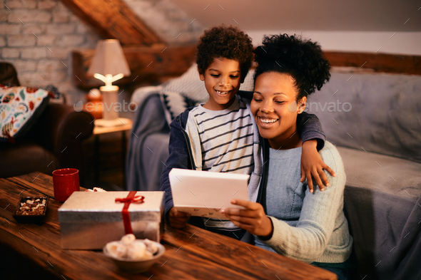 Happy black mother receiving gift and greeting card from her son on Mother\'s day.