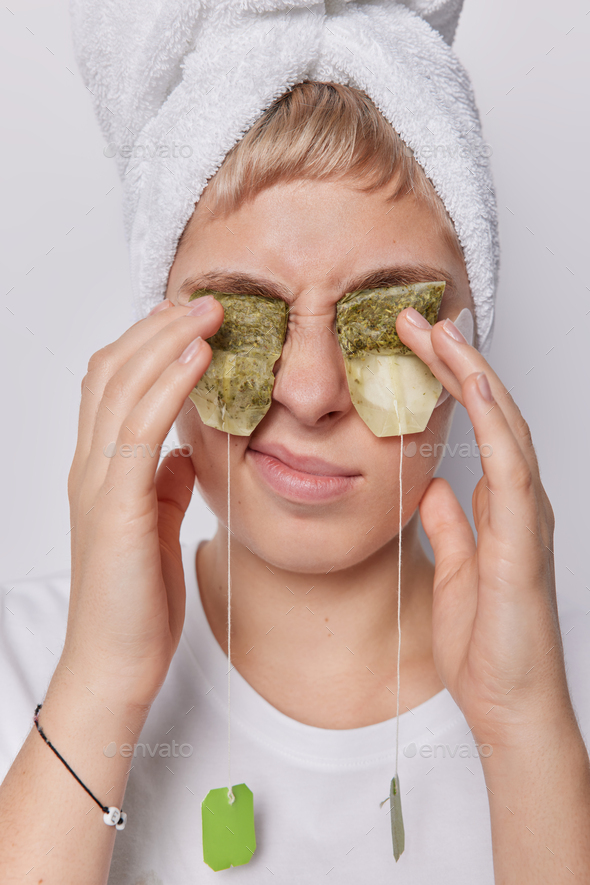 Young woman covers eyes with green tea bags for hydration and