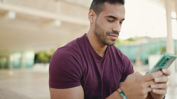 Attractive man texting on smartphone with friends while waiting them outdoor - Stock Photo - Images