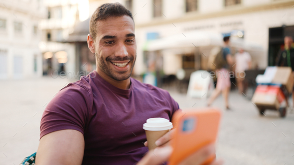 Handsome guy has video call with friend during coffee break in street cafe - Stock Photo - Images