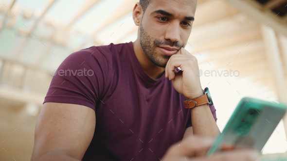 uscular man dressed casual checking his social media using smartphone outdoors - Stock Photo - Images