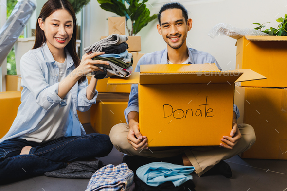 Asian volunteer man and woman packing cloth box and donate to other people and share to charity
